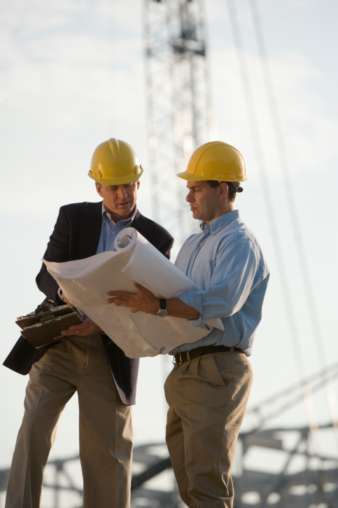 Architects with blueprints at construction site